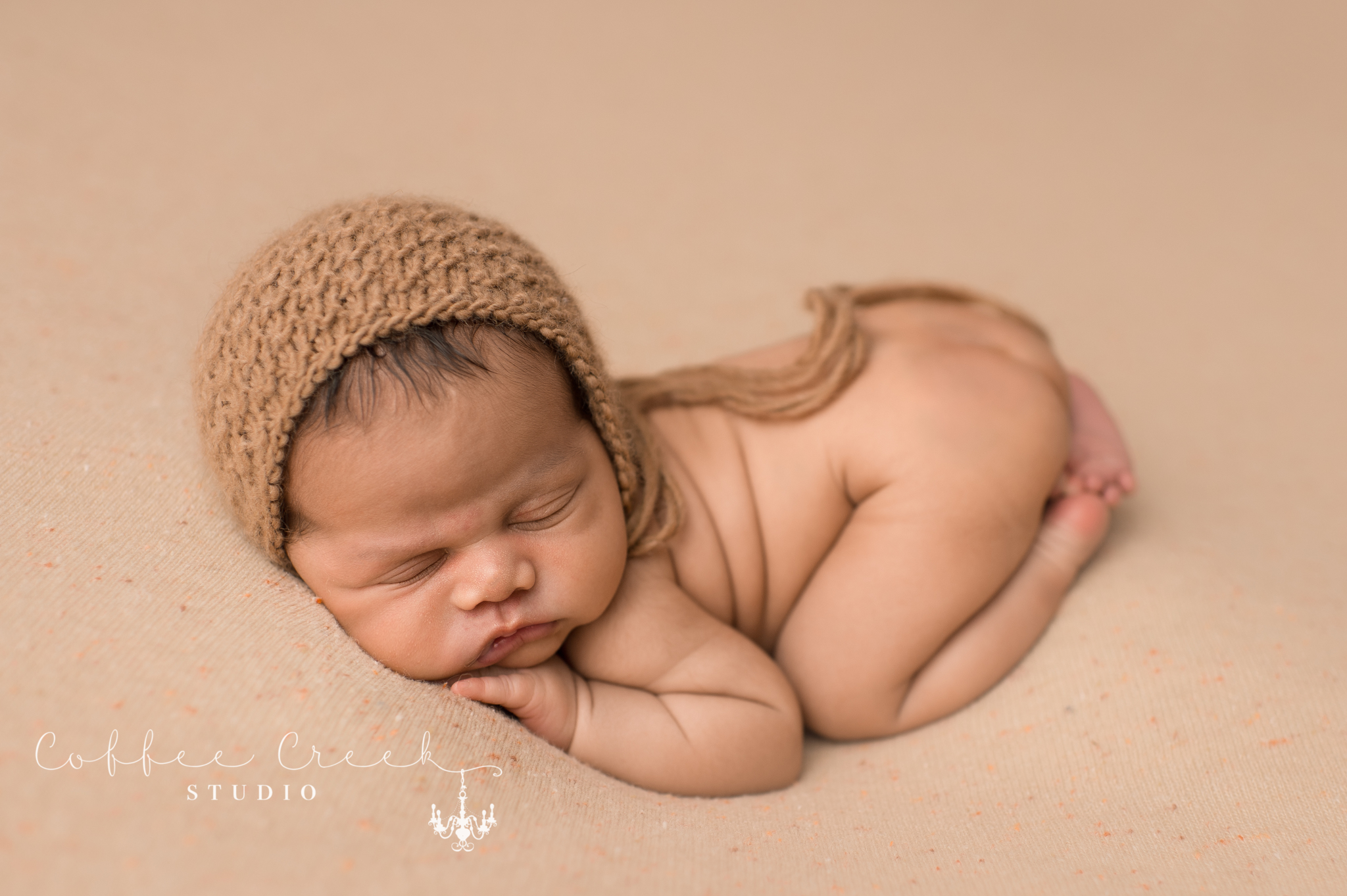 newborn baby boy sleeping posed in bonnet