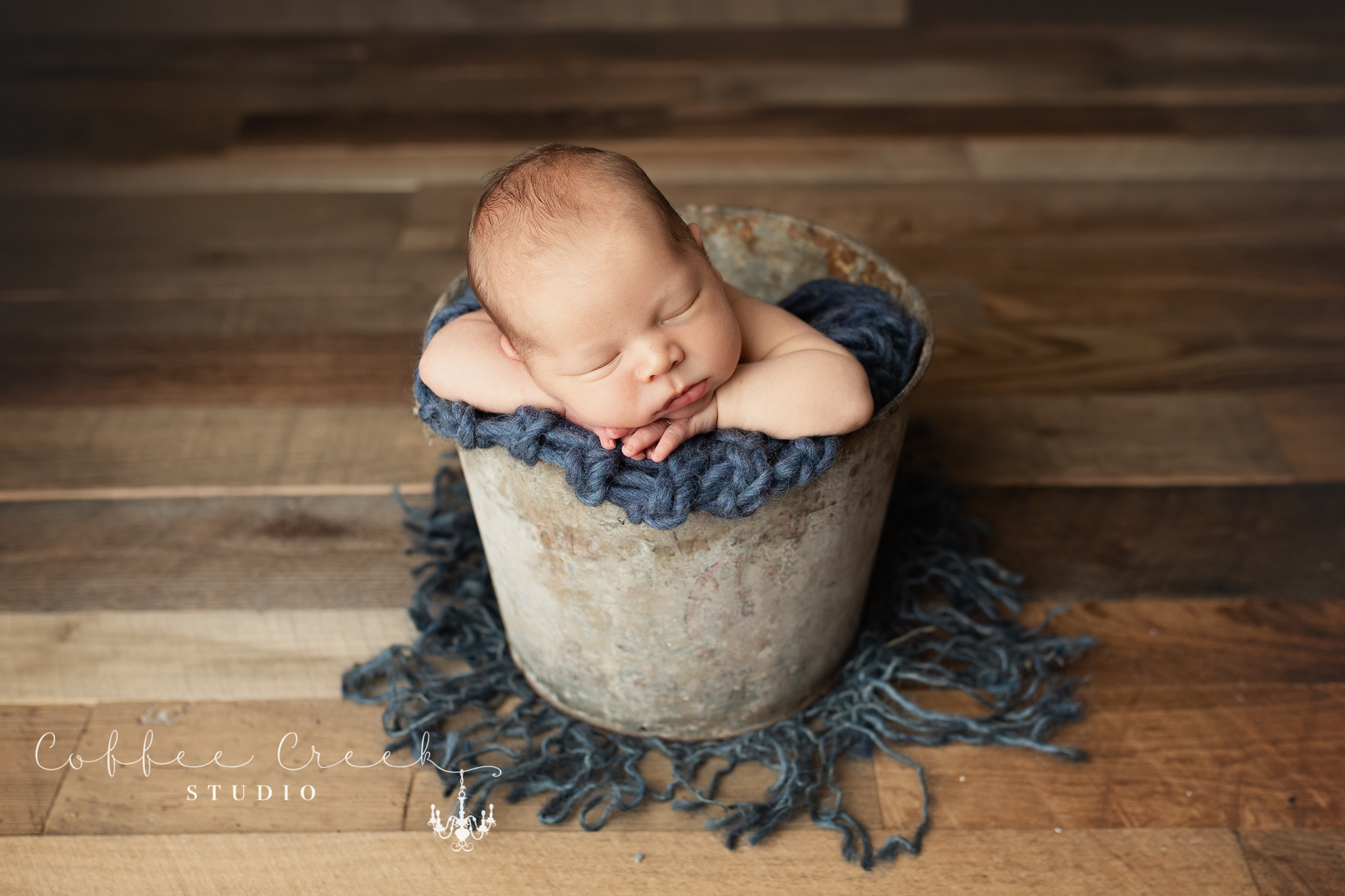 newborn baby in vintage metal bucket with blue blanket