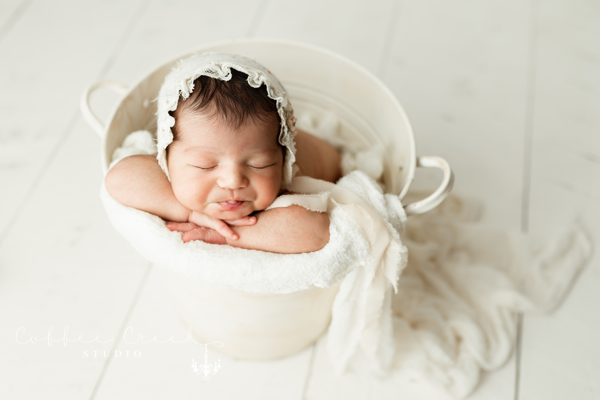 newborn baby in bucket with bonnet
