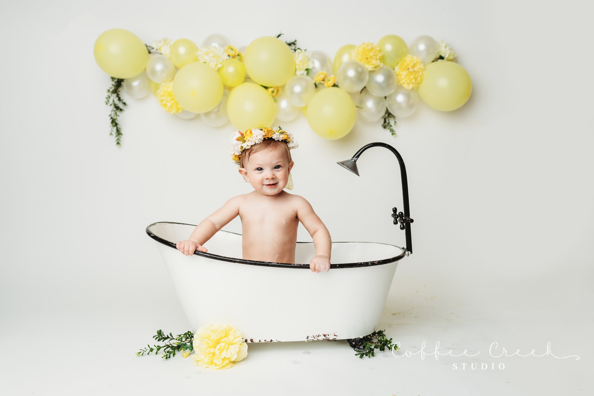 one year old in vintage bathtub with flowers and balloons